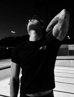 a man standing in front of a swimming pool with his arms up to the sky