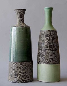 two green vases sitting next to each other on a white surface with grey background