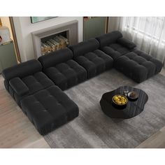 a black sectional sofa sitting on top of a gray rug