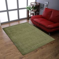 a living room with a red couch and green rug in front of a large window