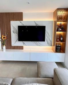 a living room with a large television mounted on the wall and built - in shelves