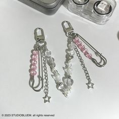 three charms are sitting on a table next to a cell phone and other items in the background