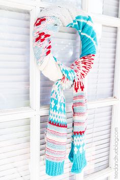 a knitted scarf hanging on the side of a window sill in front of a white shutter