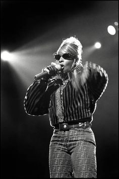 a woman standing on top of a stage with her hands in her pockets and holding a microphone