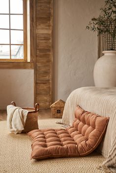 a room with a bed, basket and plant on the floor in front of it