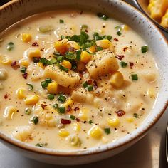 a bowl of soup with corn and cheese on the side next to some crackers