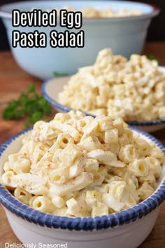 two bowls filled with macaroni salad on top of a wooden table