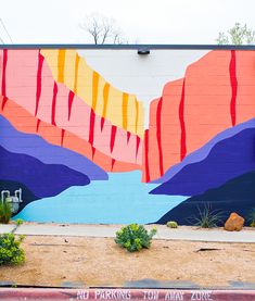 a mural painted on the side of a building with mountains and trees in the background