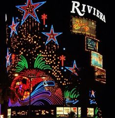 an illuminated building with lots of lights on it's sides and signs above the buildings