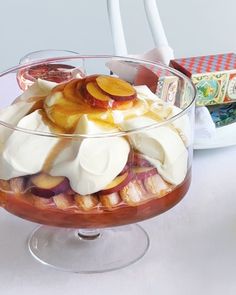 a dessert dish with fruit and whipped cream in a glass bowl on a white table