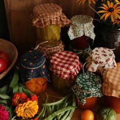 there are many jars and vegetables on the table