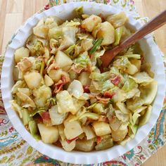 a white bowl filled with chopped vegetables on top of a colorful table cloth next to a wooden spoon