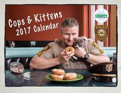 a police officer holding a kitten in his lap while sitting at a table with doughnuts