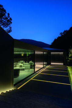 the outside of a modern house lit up at night with bright lights on the walls