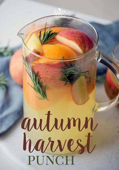 an autumn harvest punch with oranges, apples and rosemary garnish in a pitcher