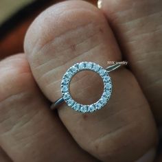 a person's hand holding a diamond ring