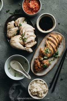 an assortment of food on plates with chopsticks and sauces next to them