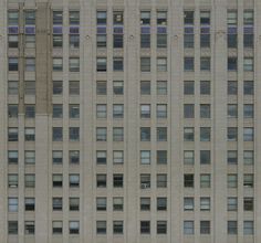 the side of a tall building with many windows on it's sides and an airplane flying by