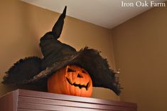 a pumpkin with a witches hat on top of it's head in a room