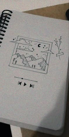 an open notebook with drawings on it sitting on top of a table next to a pen