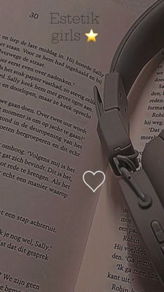 headphones laying on top of an open book with a heart - shaped ear tag