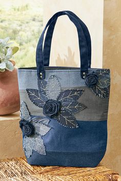 a blue bag with flowers on it sitting next to a potted plant