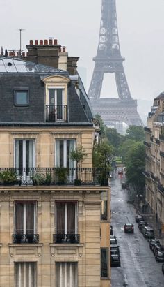 the eiffel tower is seen in the distance from an apartment building on a rainy day