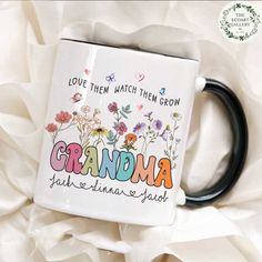 a coffee mug with the words grandma printed on it and flowers in the bottom right corner