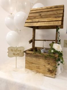 a wooden wishing well with white balloons in the background