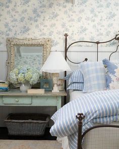 a bedroom with blue and white bedding and flowers on the nightstand next to it