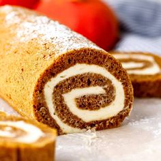 there is a roll that has been cut in half and sits on the table next to some apples