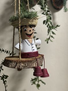 a wooden ornament with a man on it hanging from a tree branch in front of a wall