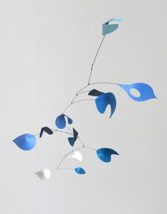 a mobile with blue and white shapes hanging from it's side on a wall