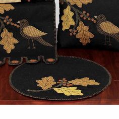 three pillows and two placemats with birds on them sitting on a wooden table