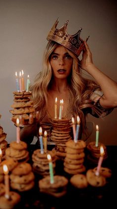 a woman with a crown on her head standing in front of stacks of donuts