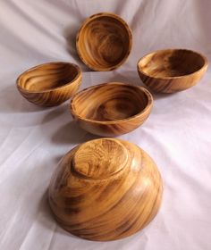 four wooden bowls sitting on top of a white sheet