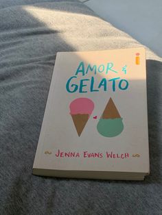 a book with an ice cream cone on it sitting on top of a bed next to a pillow