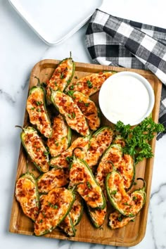 stuffed jalapenos on a cutting board with ranch dressing