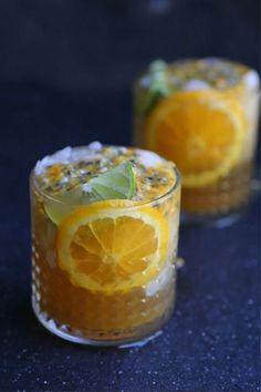 two glasses filled with orange slices and garnish on top of a blue table