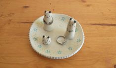 three small white ceramic animals on a plate with two rings in the shape of bears