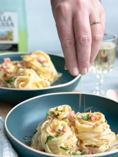 a person is sprinkling parmesan cheese onto some pasta in a blue bowl