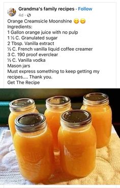 four jars filled with orange juice sitting on top of a table