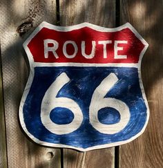 a close up of a street sign on a wooden fence with the word route 66 painted on it