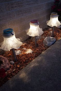 three lights that are sitting in the ground next to some rocks and stones on the ground