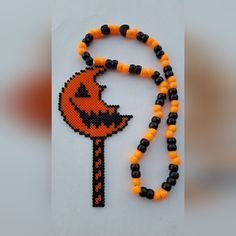 an orange and black beaded necklace with a halloween pumpkin on it, hanging from a string