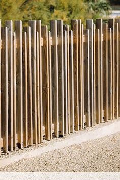 a man riding a skateboard down a street next to a tall wooden fence with slats on it