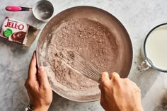 someone mixing ingredients in a bowl on top of a marble table with milk and eggs