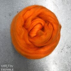 an orange wool roving sitting on top of a cement floor next to a white wall