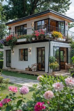 a white house with lots of flowers on the balcony