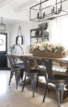 a dining room table with chairs and flowers on the centerpiece in front of it